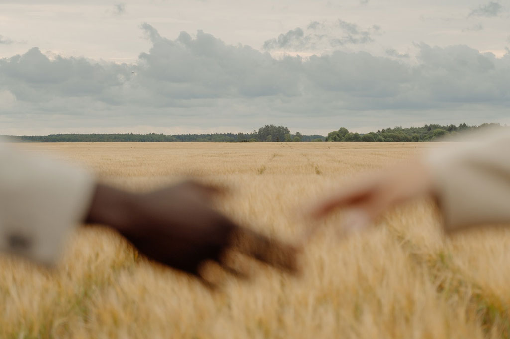 A blurred picture of two hands reaching each other in a field