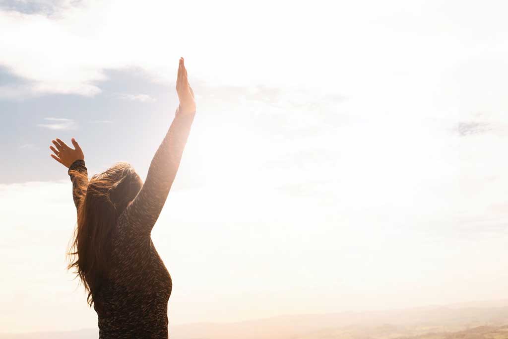 A woman raising both hands in the sun